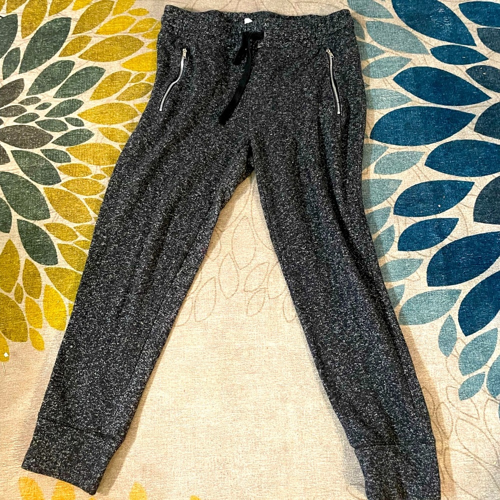 Charcoal grey sweatpants that tie at waist and have two zipper pockets